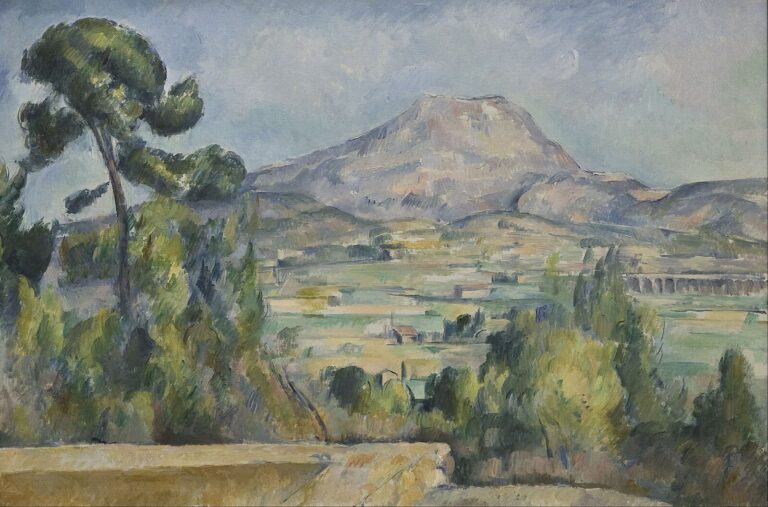 Mont Sainte-Victoire rises beyond green and yellow agricultural fields, village houses, trees, a yellowish terrace wall, and a leaning pine beneath a pale blue-grey sky.