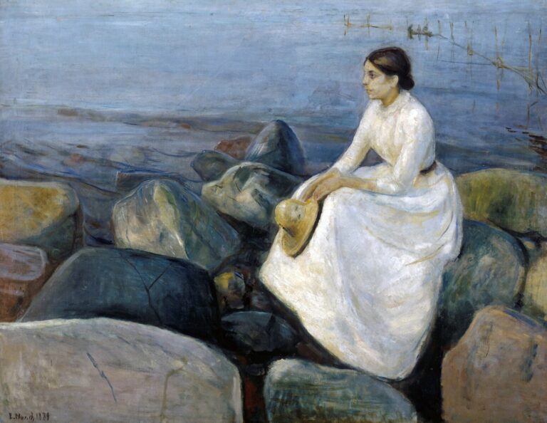 A young woman dressed in white sits on large rocks along a dark blue Norwegian shoreline, holding a hat in her lap and gazing into the distance across the calm sea.
