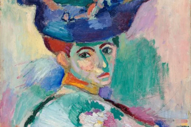 Woman with a Hat (1905) — Matisse’s Fauvist Explosion Henri Matisse’s Woman with a Hat shows Amélie Matisse seated in a large decorated hat, her face and clothing constructed through vivid green, orange, blue, violet, and red brushstrokes rather than naturalistic flesh tones.